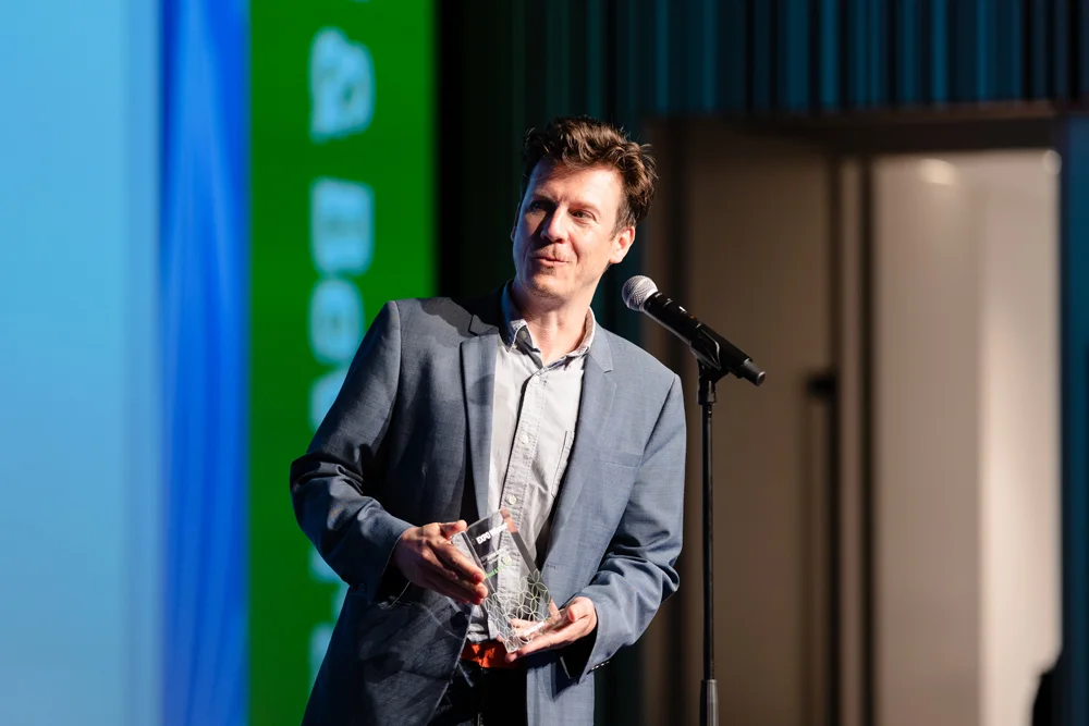 Andrew Tait holding an award at a microphone at the 2022 Plug and Play Japan summit